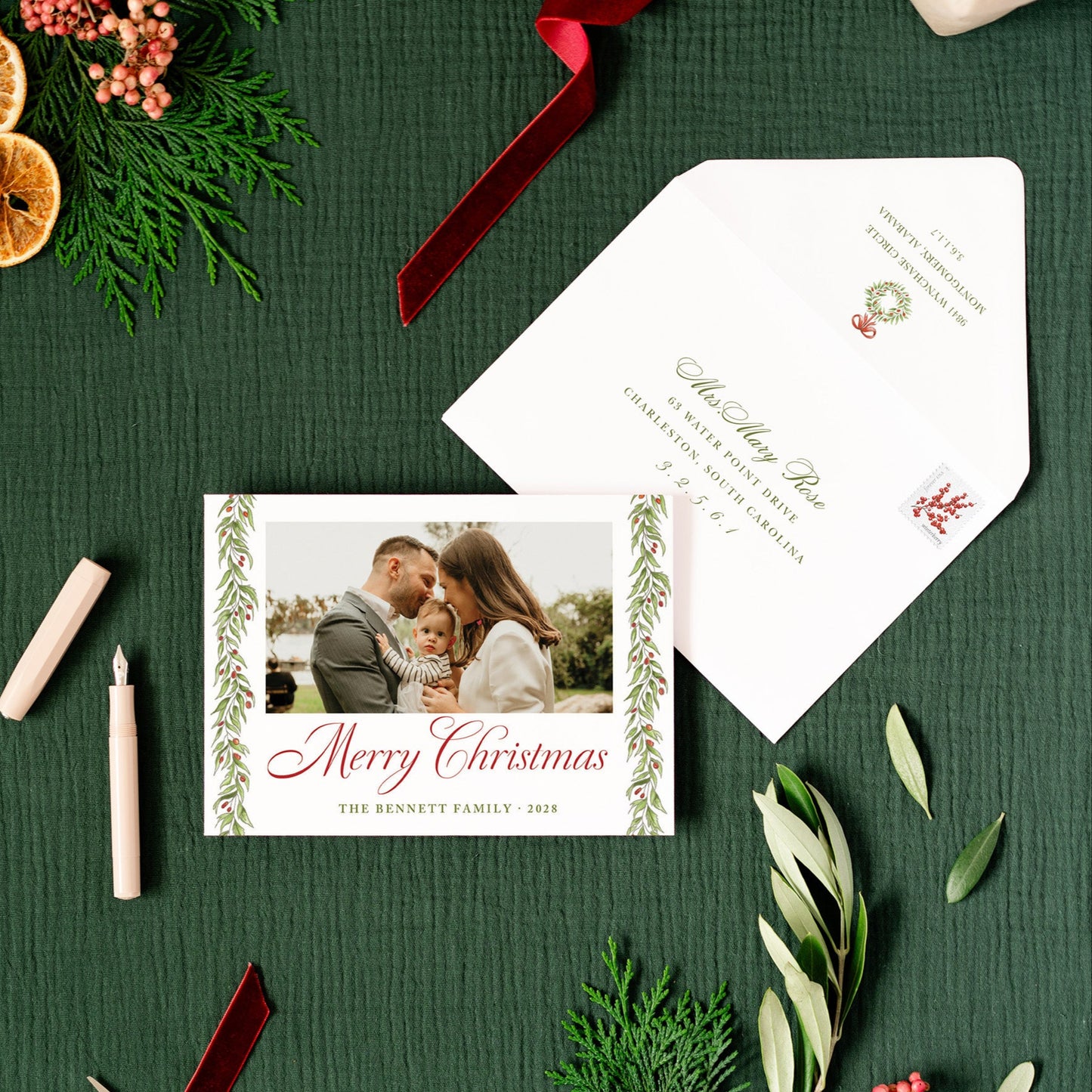Christmas card with envelope, candles, and decorative elements on a green surface