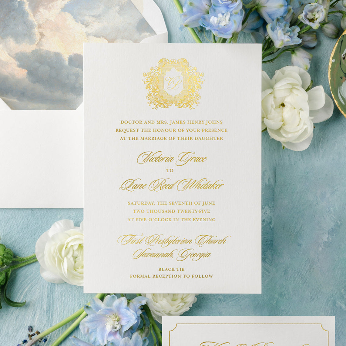 Wedding invitation card with gold foil on a light blue background with flowers