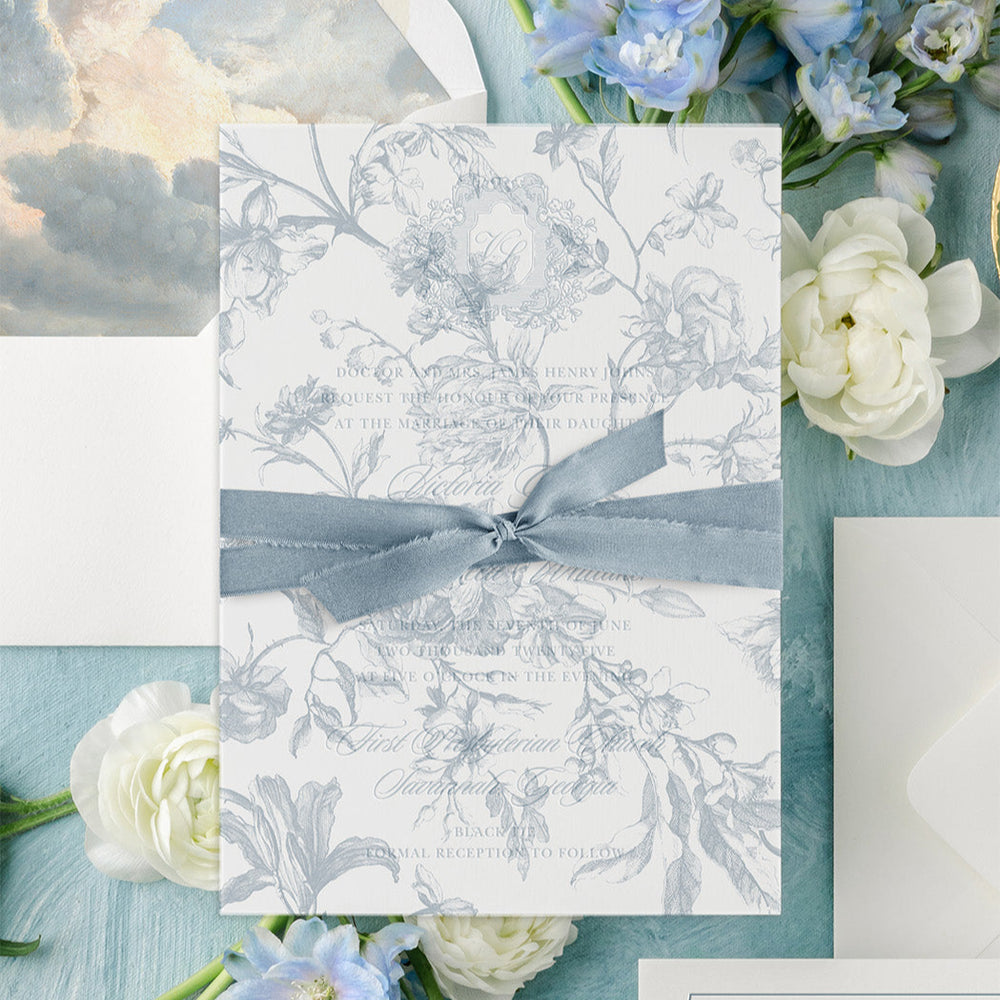 Decorative card with floral design and blue ribbon on a background of flowers and watercolor elements.
