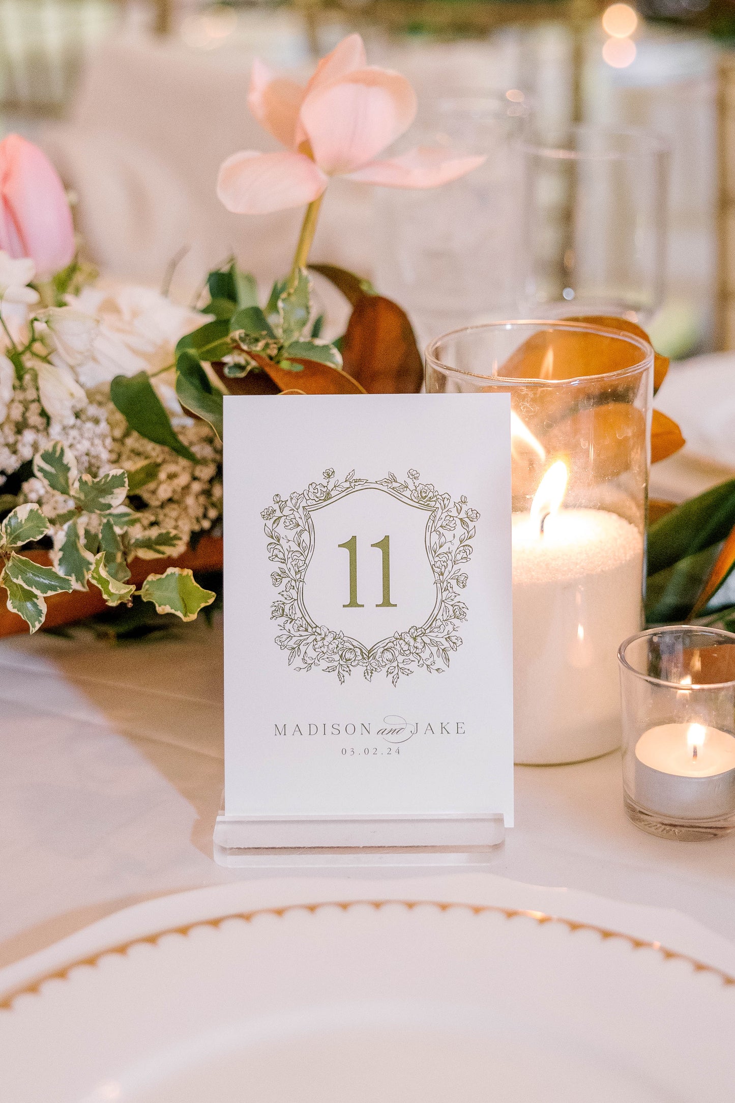 Table setting with a floral arrangement, candles, and a table number card.